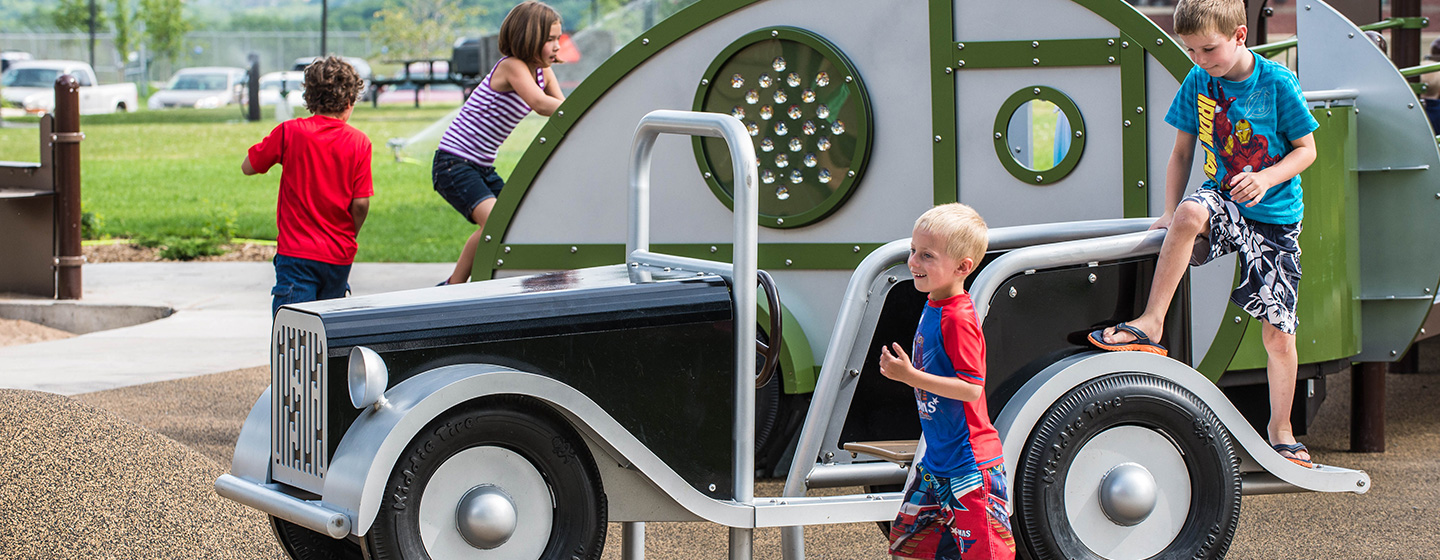 Group of young kids running and jumping around a playground with nature-inspired steppers and climbers.