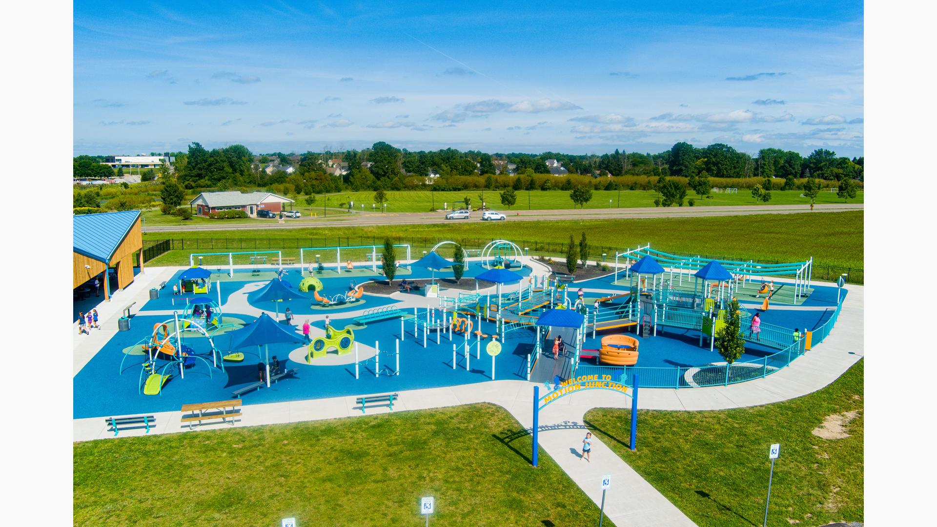 Elevated view of a large inclusive playground filled with playing families.