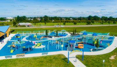 Elevated view of a large inclusive playground filled with playing families.
