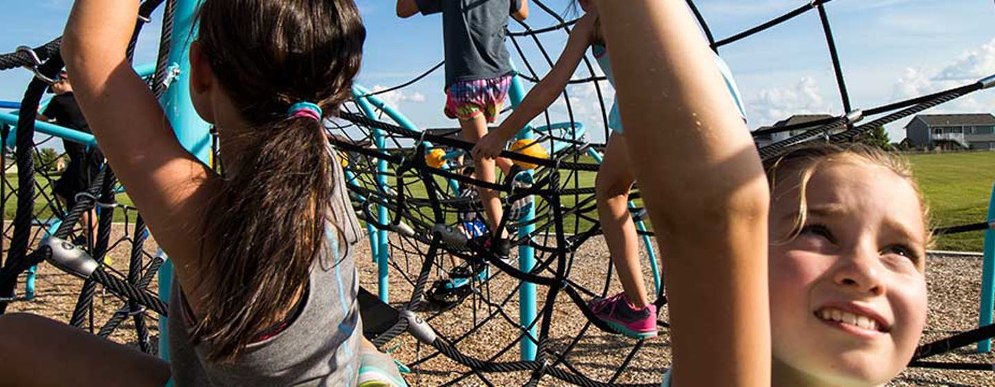Two girls climb inside a netted rope climber tunnel at Eldorado Park in Clearwater Minnesota.