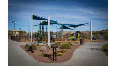 Parents watch from benches as their kids play on the PlayBooster and Smart Play  play systems. SkyWays shade panels cover the playground.