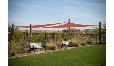 Two benches under two maroon colored shade sails.